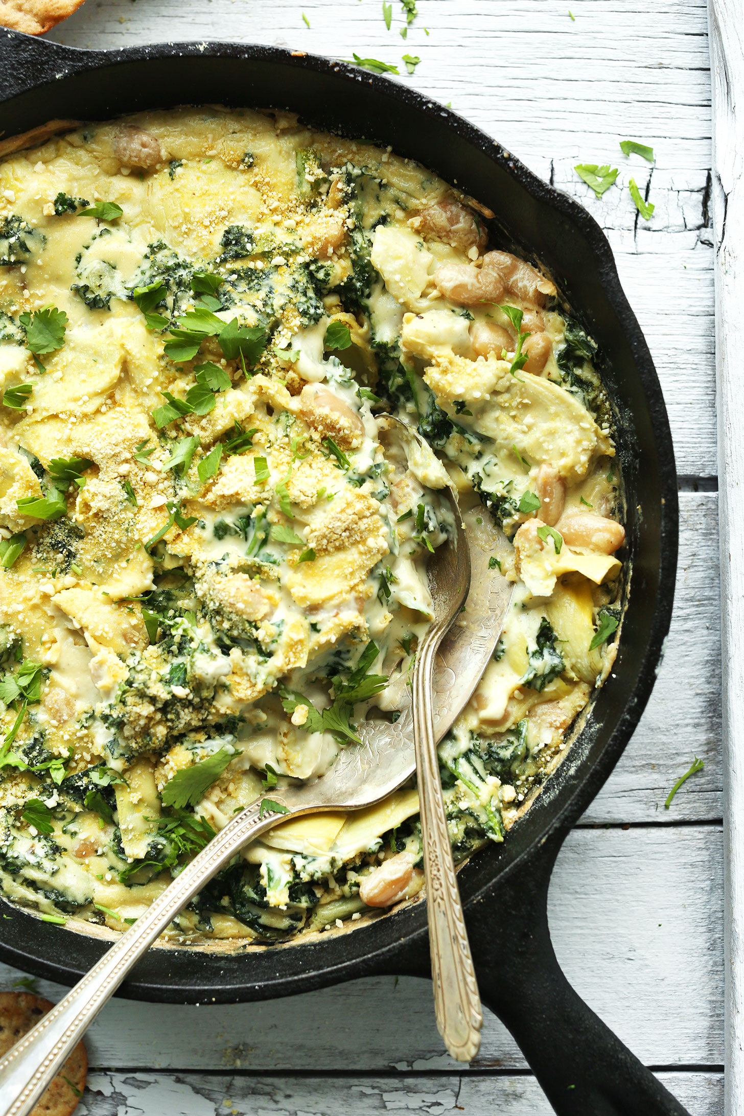 Cast-iron skillet filled with flavorful and delicious Kale & White Bean vegan Artichoke Dip