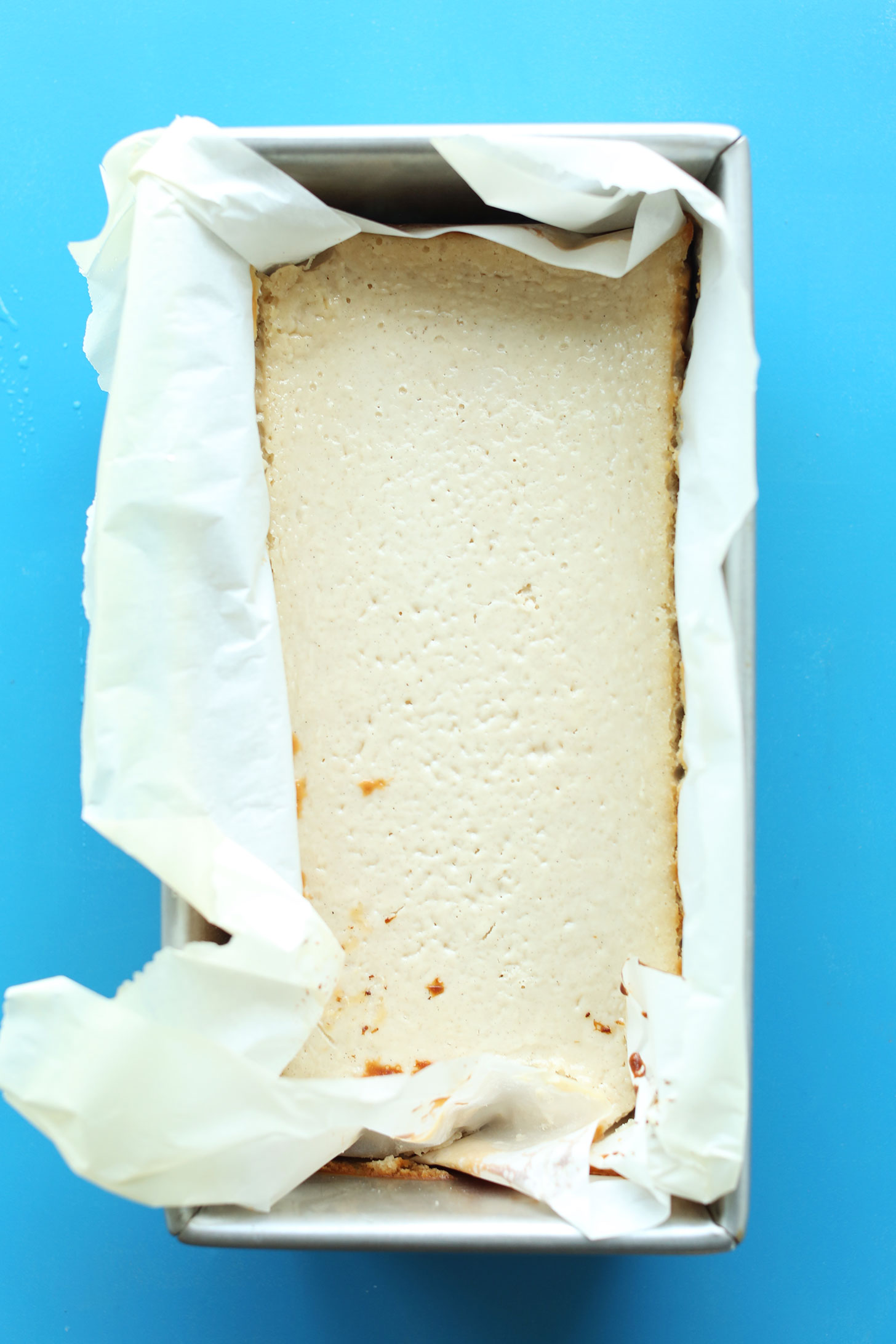 Parchment-lined bread pan with our gluten-free vegan Baked Cheesecake