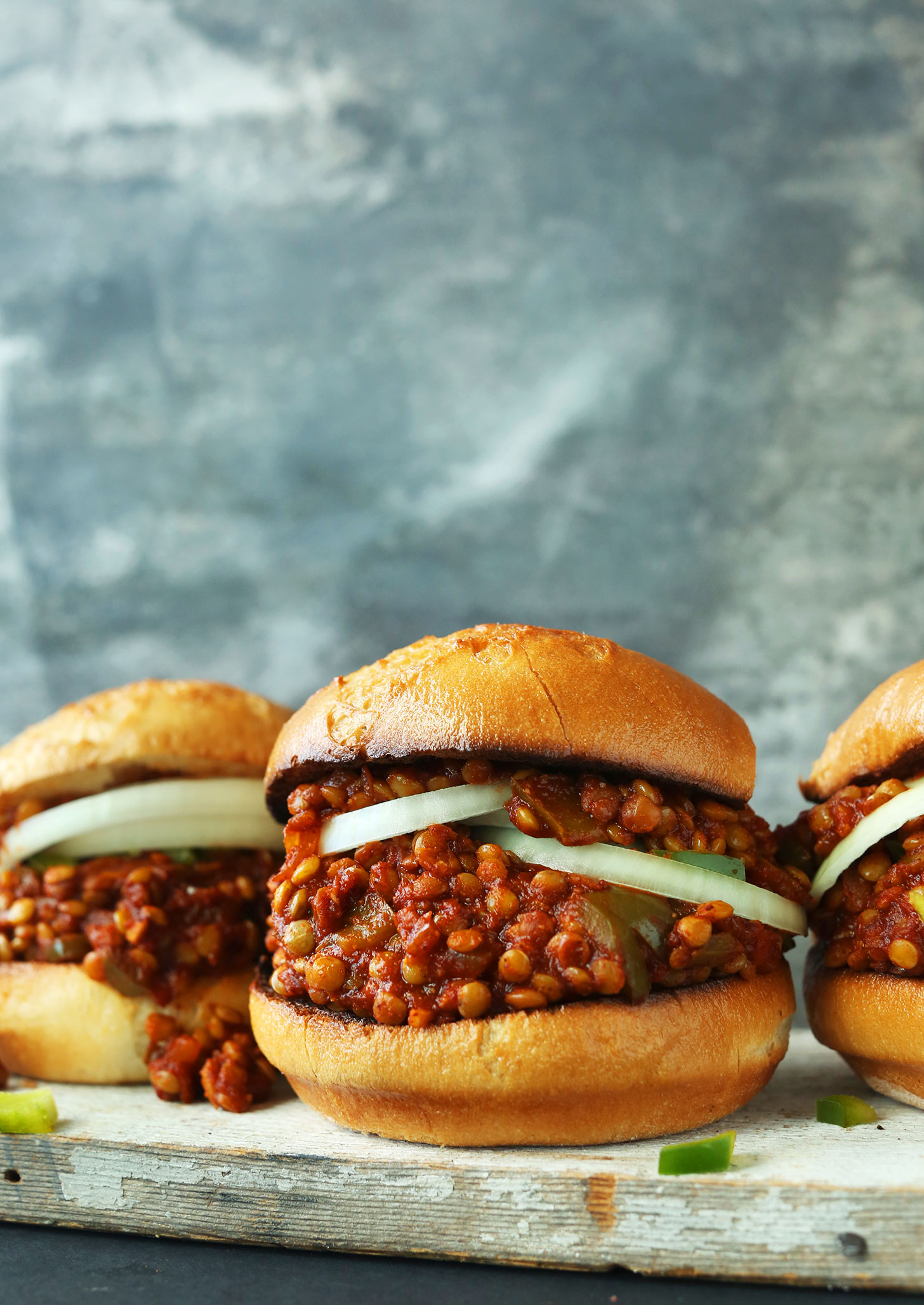 Buns filled with onion slices and Simple Vegan Sloppy Joes for a hearty plant-based meal