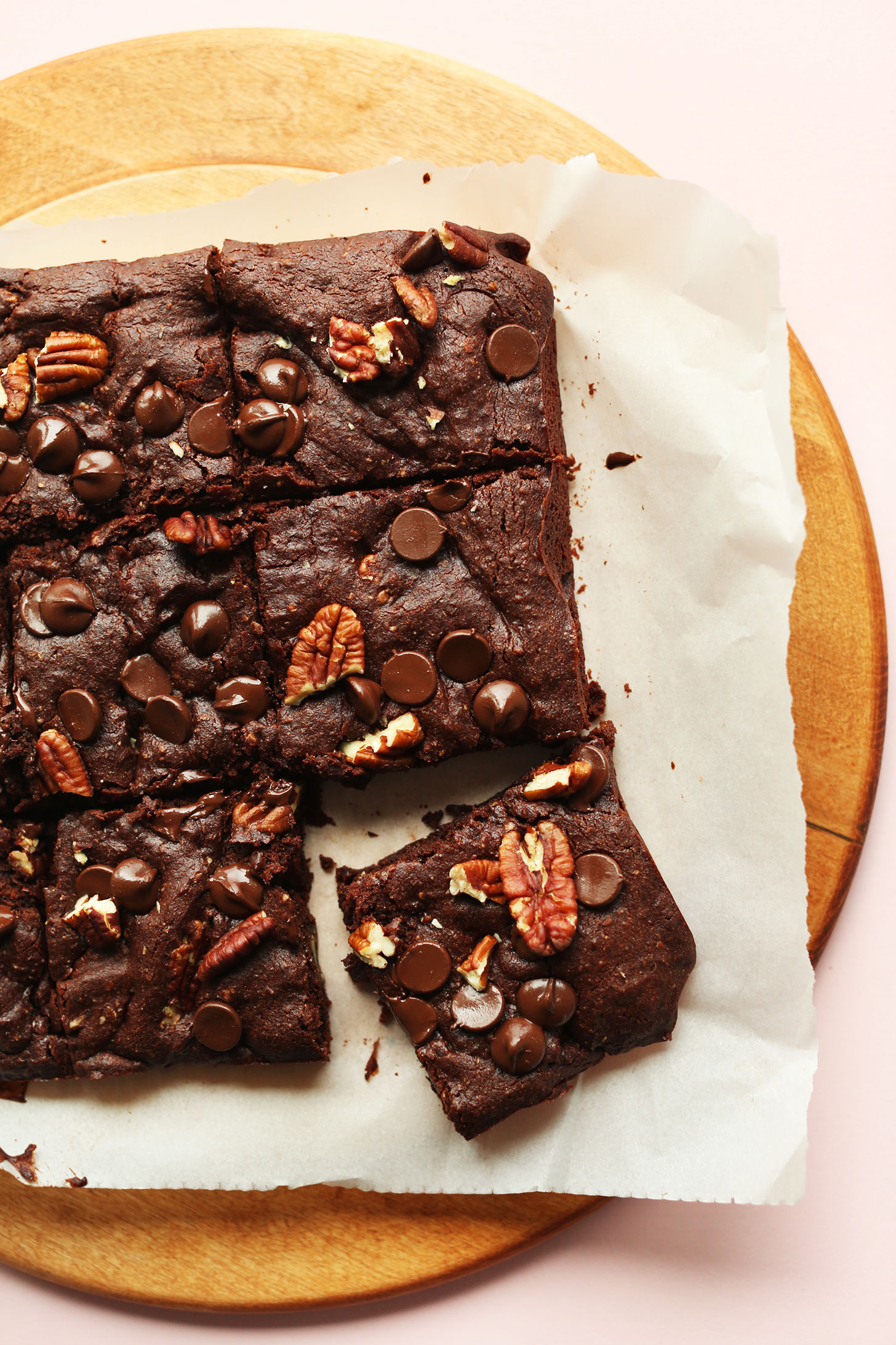 Parchment paper with squares of Fudgy Vegan Gluten-Free Brownies with dark chocolate and pecans