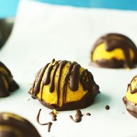 Parchment-lined baking sheet of Golden Milk Macaroons topped with a dark chocolate drizzle