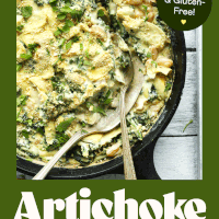 Serving spoons in a cast iron skillet of Kale & White Bean Artichoke Dip