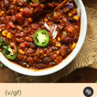 Bowl of vegan chili topped with red onion and jalapeno