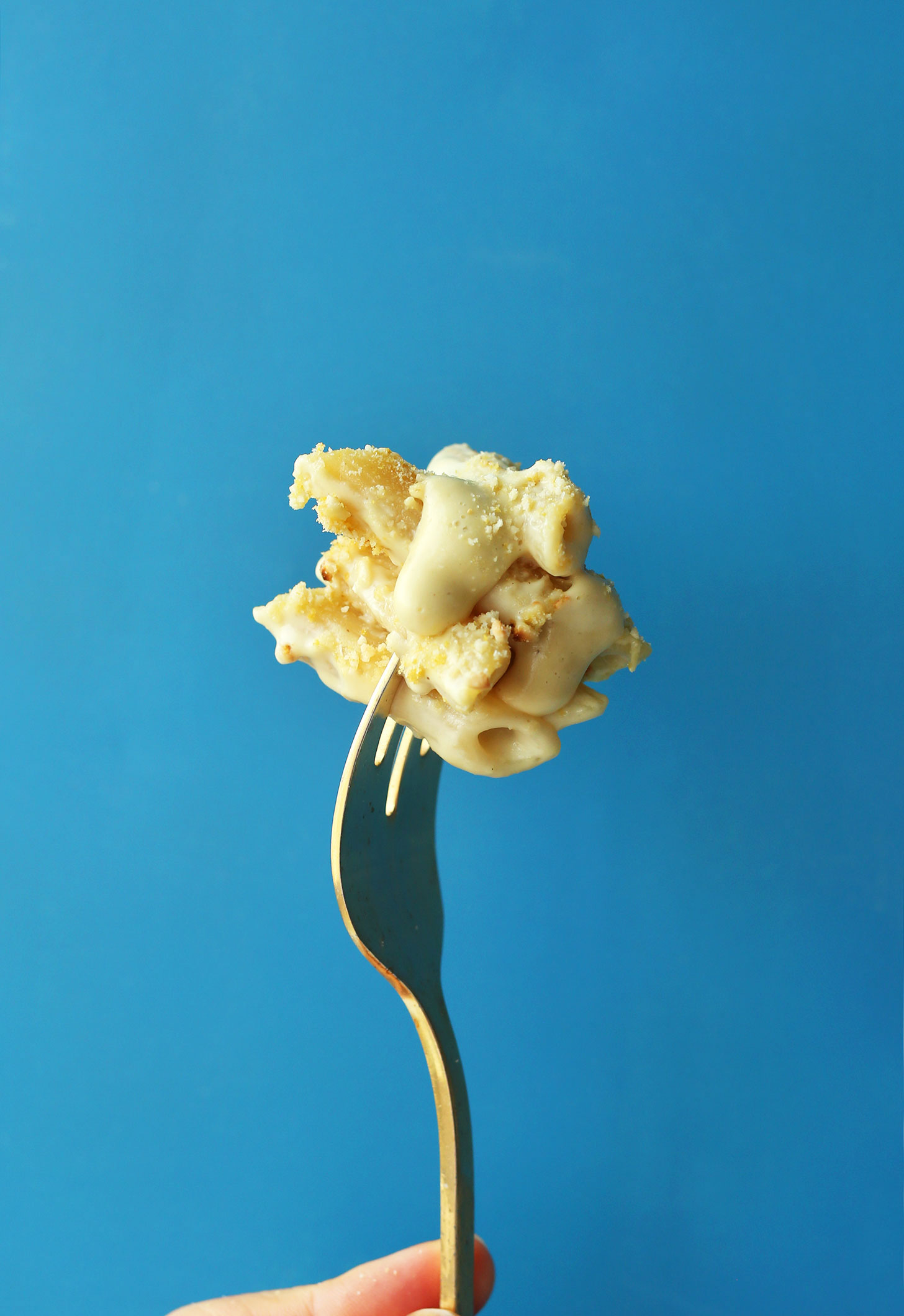Holding up a bite of the best vegan gluten-free mac n cheese recipe on a fork