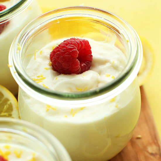 Jars of Vegan Lemon Curd topped with lemon zest and fresh raspberries