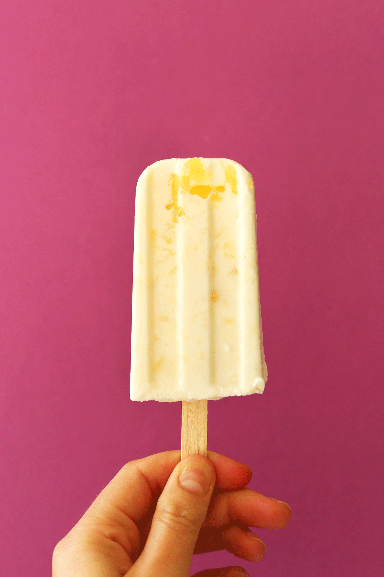 Holding a Pina Colada Popsicle against rotating color backgrounds
