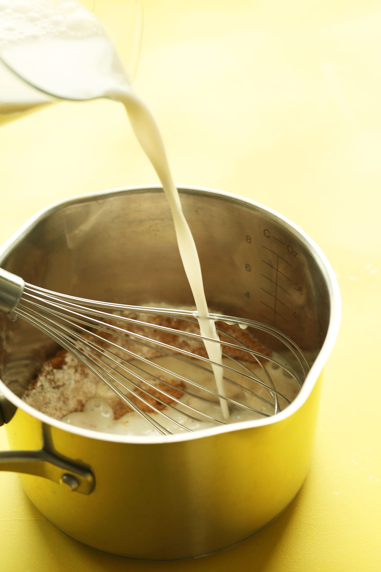 Pouring nut-milk into a saucepan full of spices for making homemade Banana Cream Pie