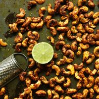 Baking sheet of homemade Curry Spiced Cashews and a lime half