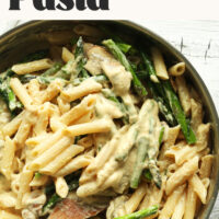 Pan of mushroom and asparagus pasta with text above it saying vegan and gluten-free