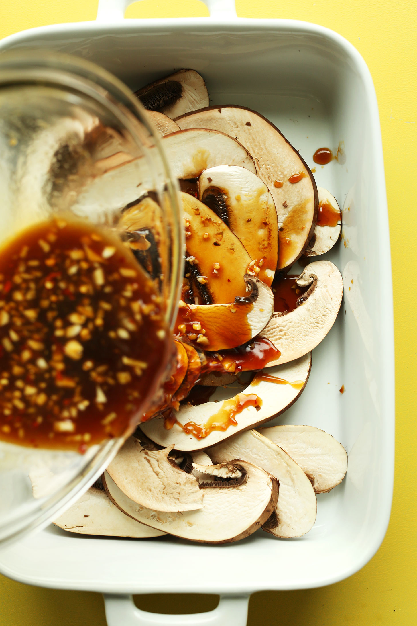 Pouring sauce over sliced portobello mushrooms for plant-based stir fry