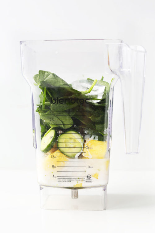 Blender filled with ingredients for our refreshing Cucumber Smoothie with Pineapple, Greens, Lime and Coconut