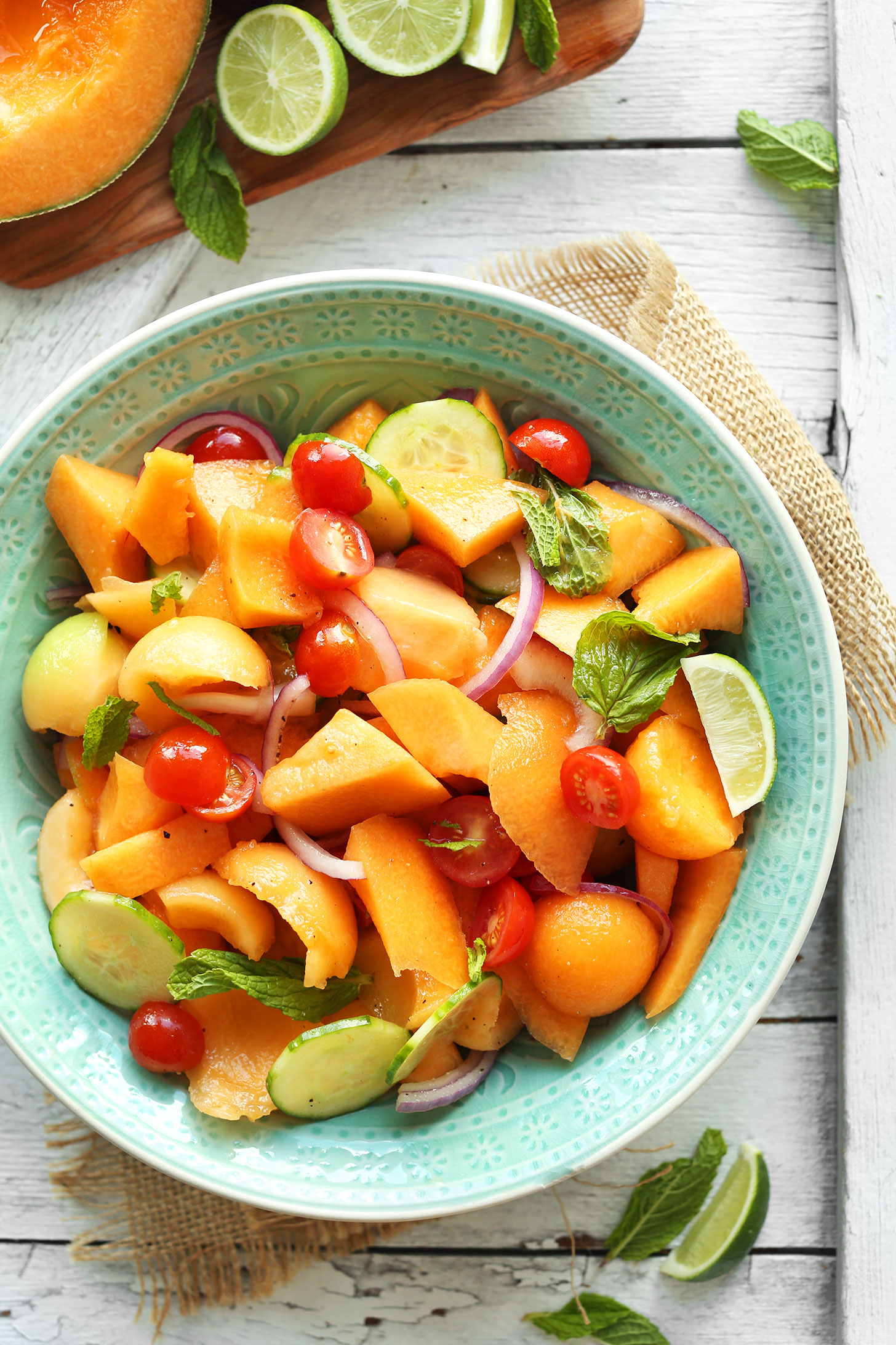 Bowl of our easy vegan summer salad made with Tomato, Cucumber, Cantaloupe, and fresh mint