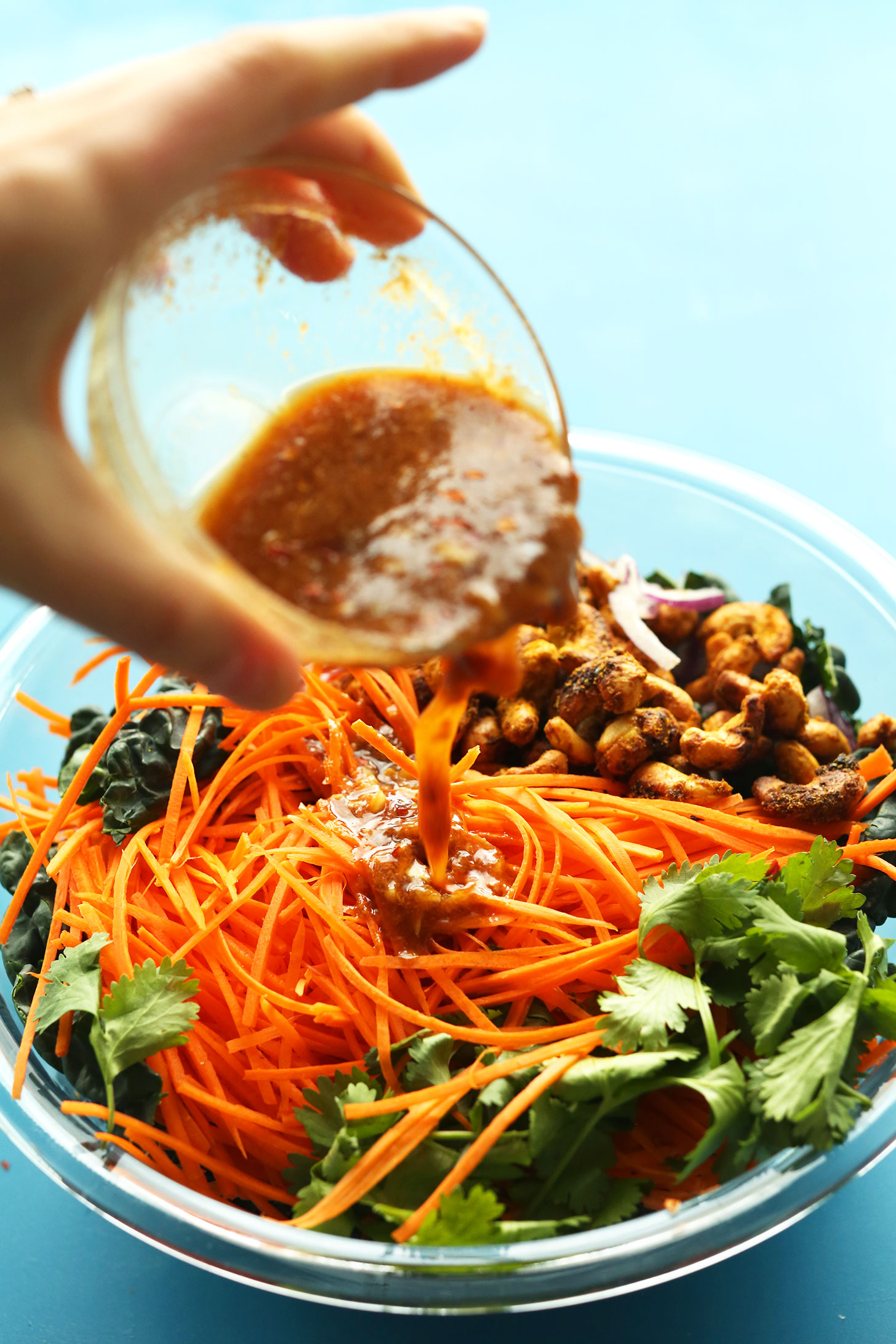 Pouring dressing onto our Easy Thai Carrot Salad with Curried Cashews