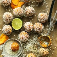 Cookie scoop, shredded coconut, lime half, and homemade Mango Energy Bites