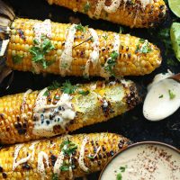 Baking sheet with Grilled Corn drizzled with Vegan Sriracha Aioli