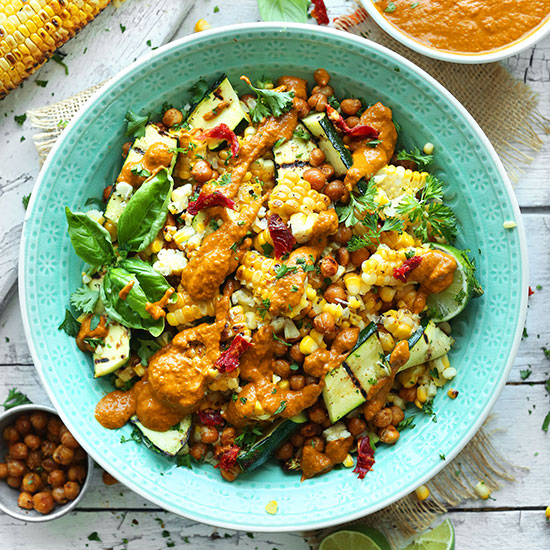 Teal bowl filled with Grilled Corn & Zucchini Salad with Sun-Dried Tomato Vinaigrette