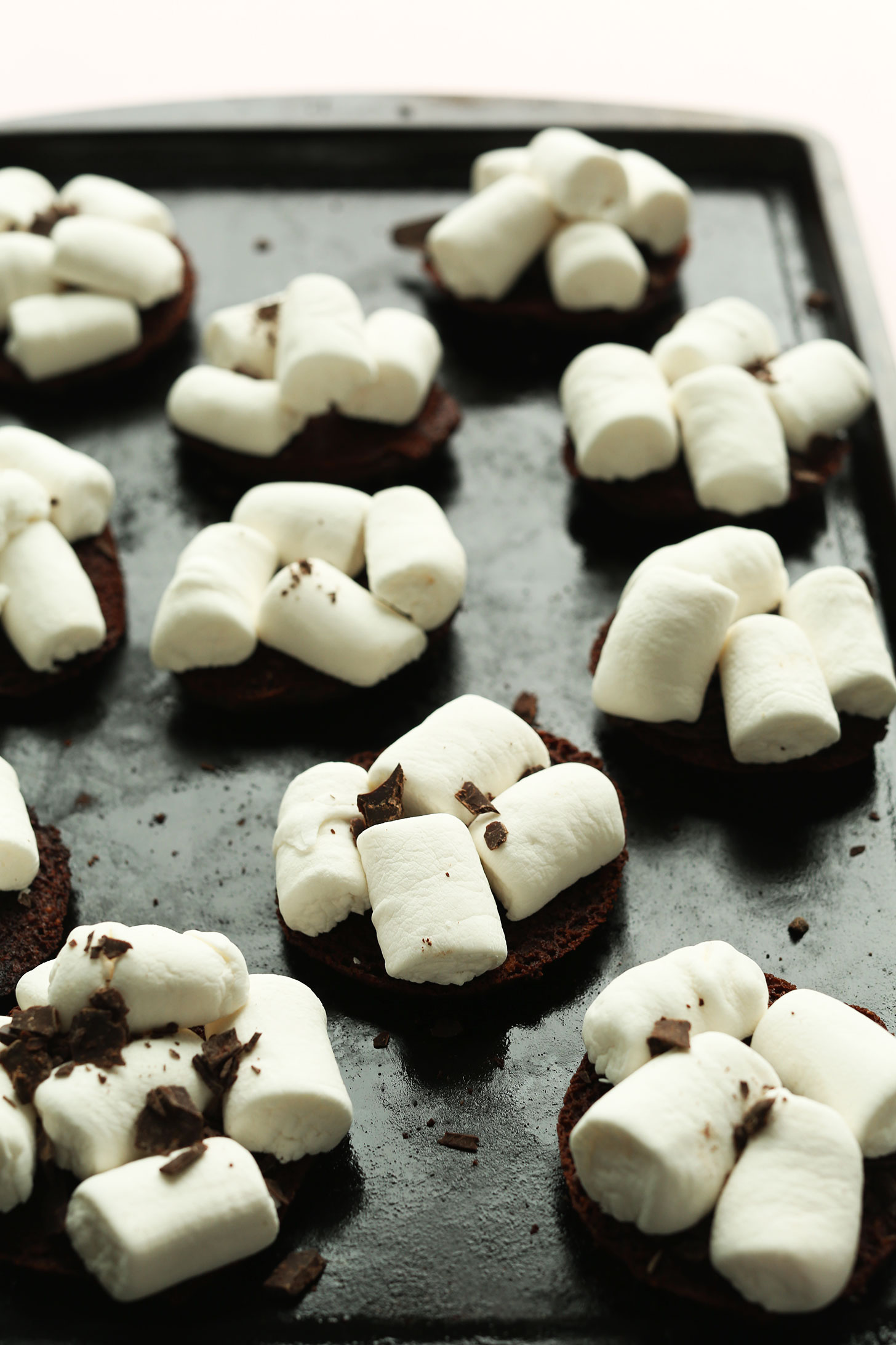 Baking sheet with gluten-free chocolate cookies topped with vegan marshmallows