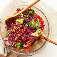 Wooden salad spoons in a glass bowl filled with Asian Quinoa Salad