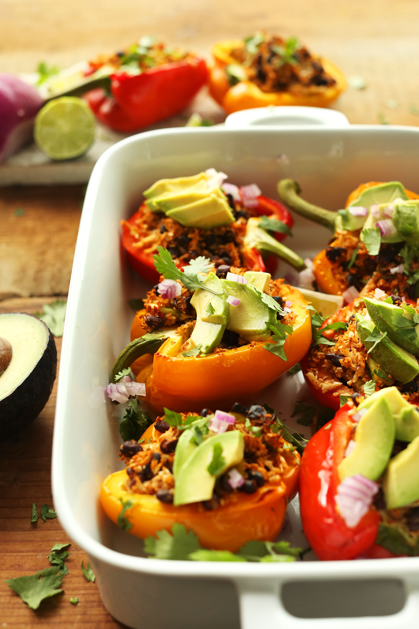 Mexican Cauliflower Rice Stuffed Peppers topped with red onion, cilantro, and fresh avocado