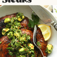 Two grilled portobello steaks in a bowl with avocado chimichurri