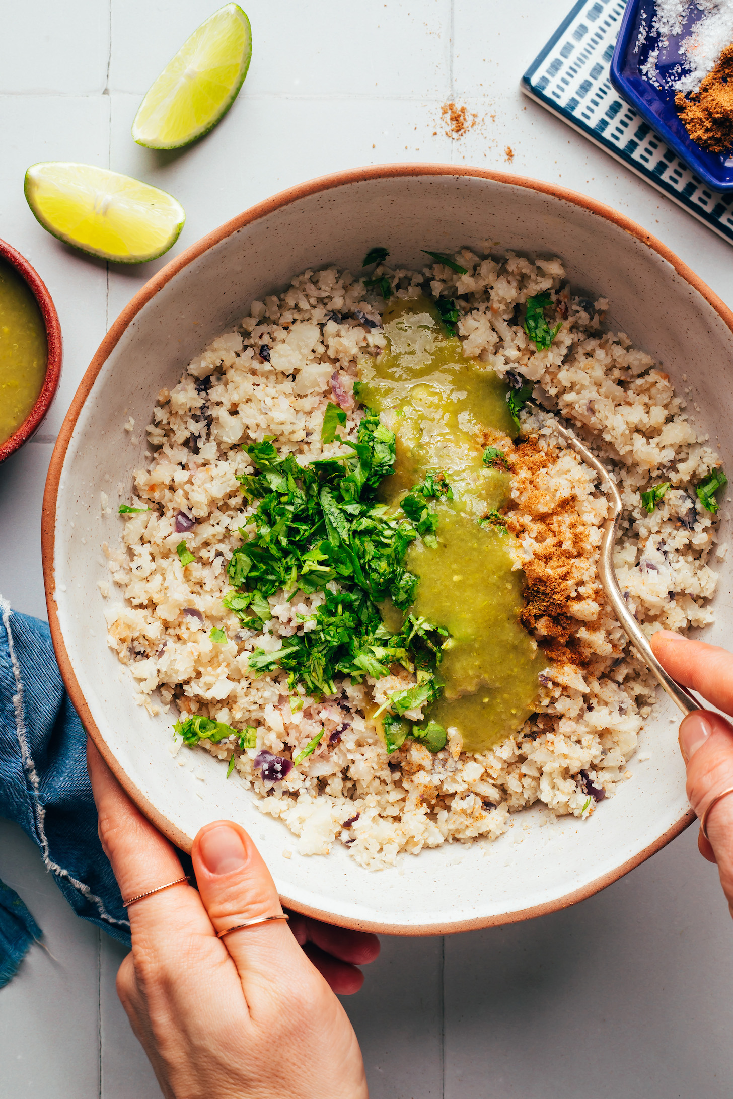 Stirring salsa, spices, and cauliflower rice in a bowl