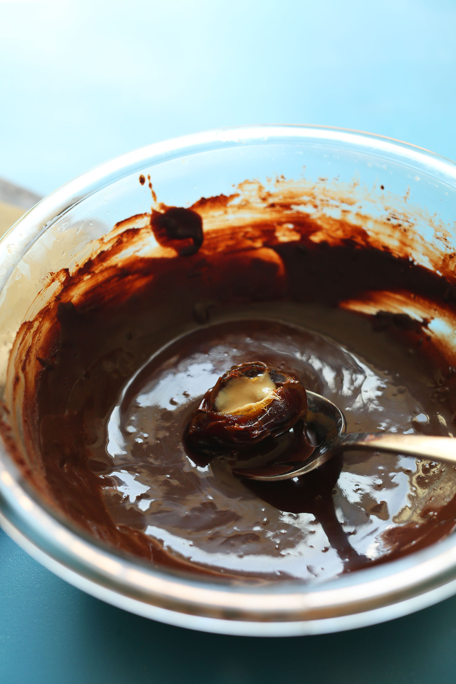 Dipping a Tahini-Stuffed Date in homemade vegan dark chocolate for an easy dessert recipe