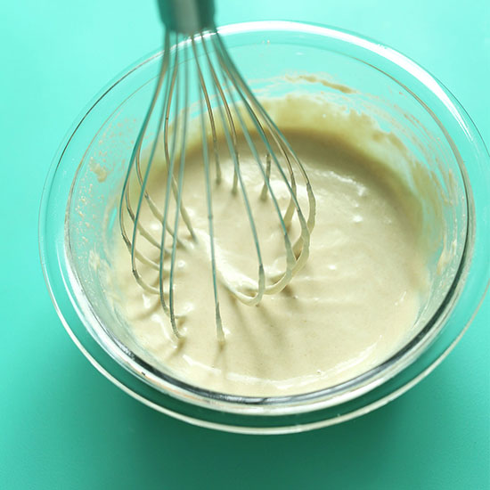 Using a whisk to mix a bowl of simple homemade tahini sauce