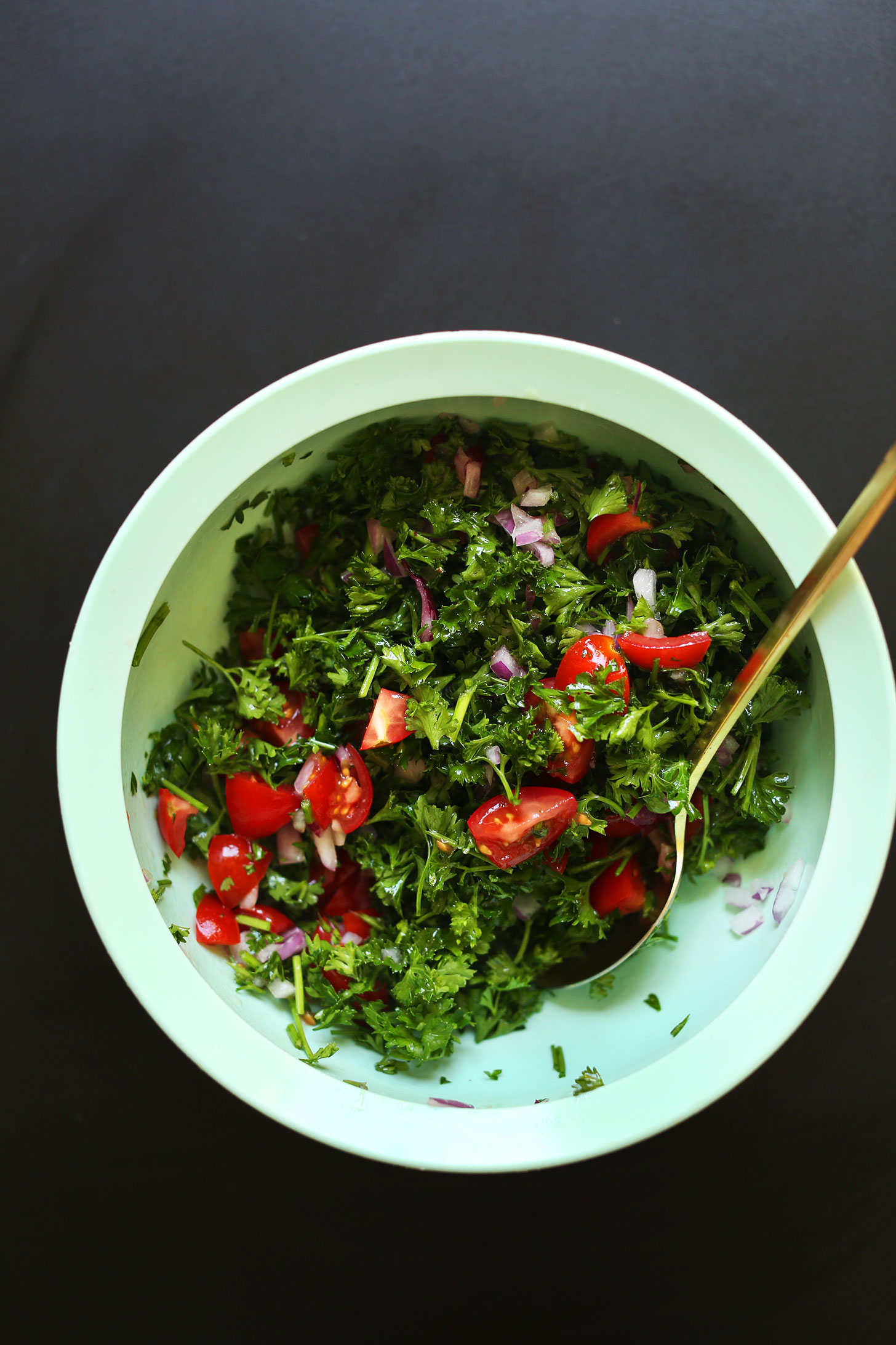 Stirring together ingredients for a parsley salad for vegan Mediterranean Bowls