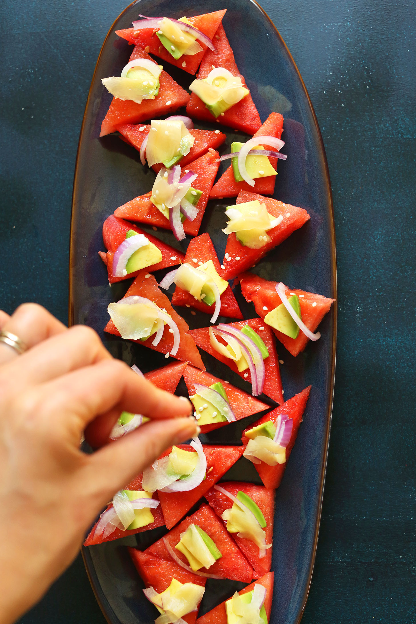 Sprinkling sesame seeds onto vegan Watermelon Sashimi for a vegan summer appetizer