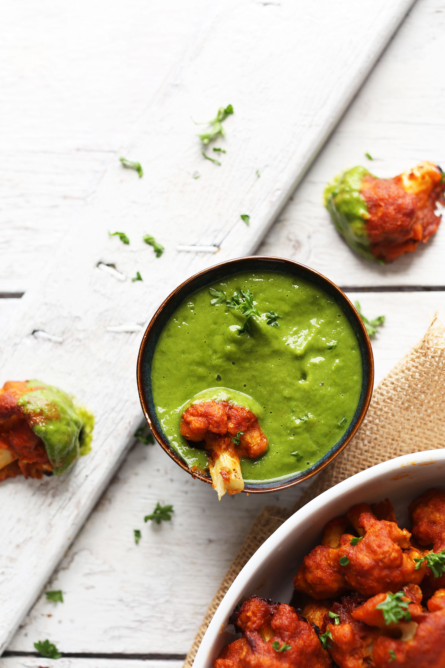 Dipping Red Curry Cauliflower into Green Chutney for a delicious vegan appetizer