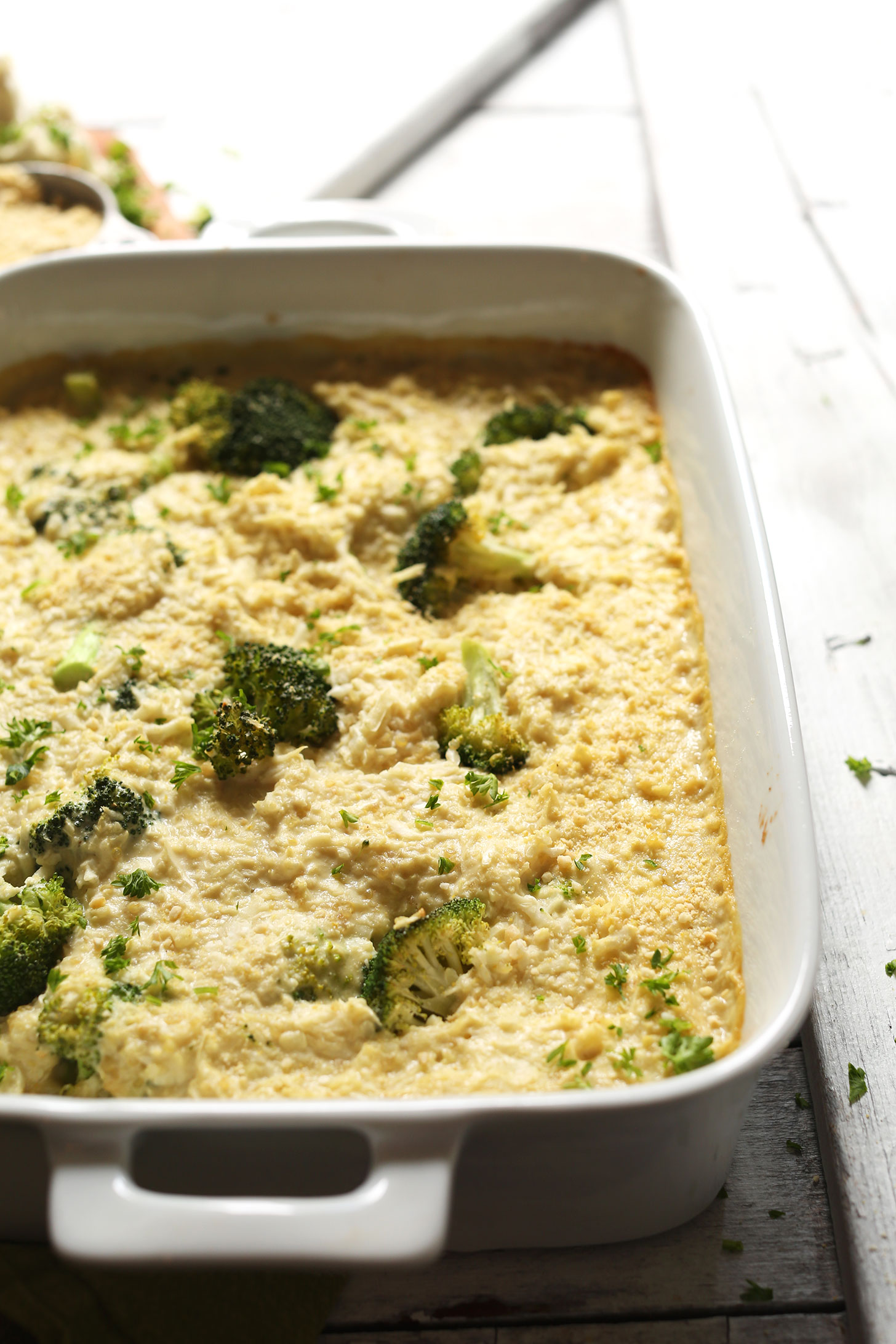 Ceramic baking dish with Cheesy Cauliflower Rice Broccoli Bake for a gluten-free plant-based side dish