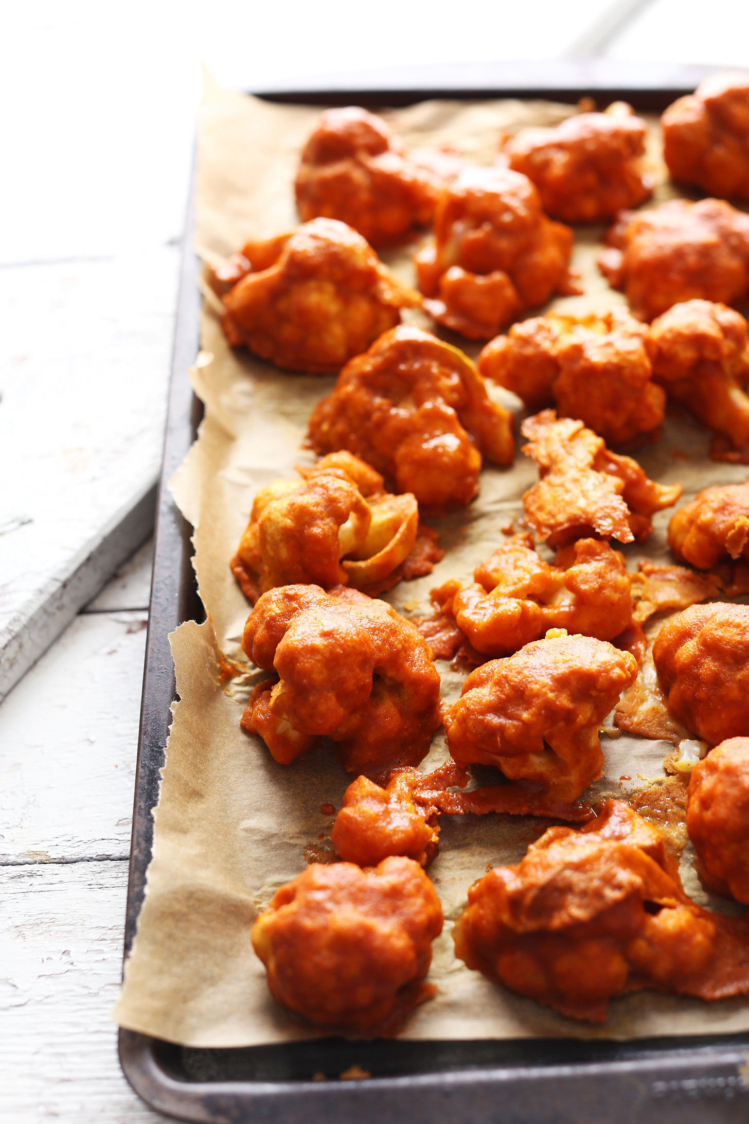 Saucy vegan Red Curry Cauliflower Wings on a parchment-lined baking sheet