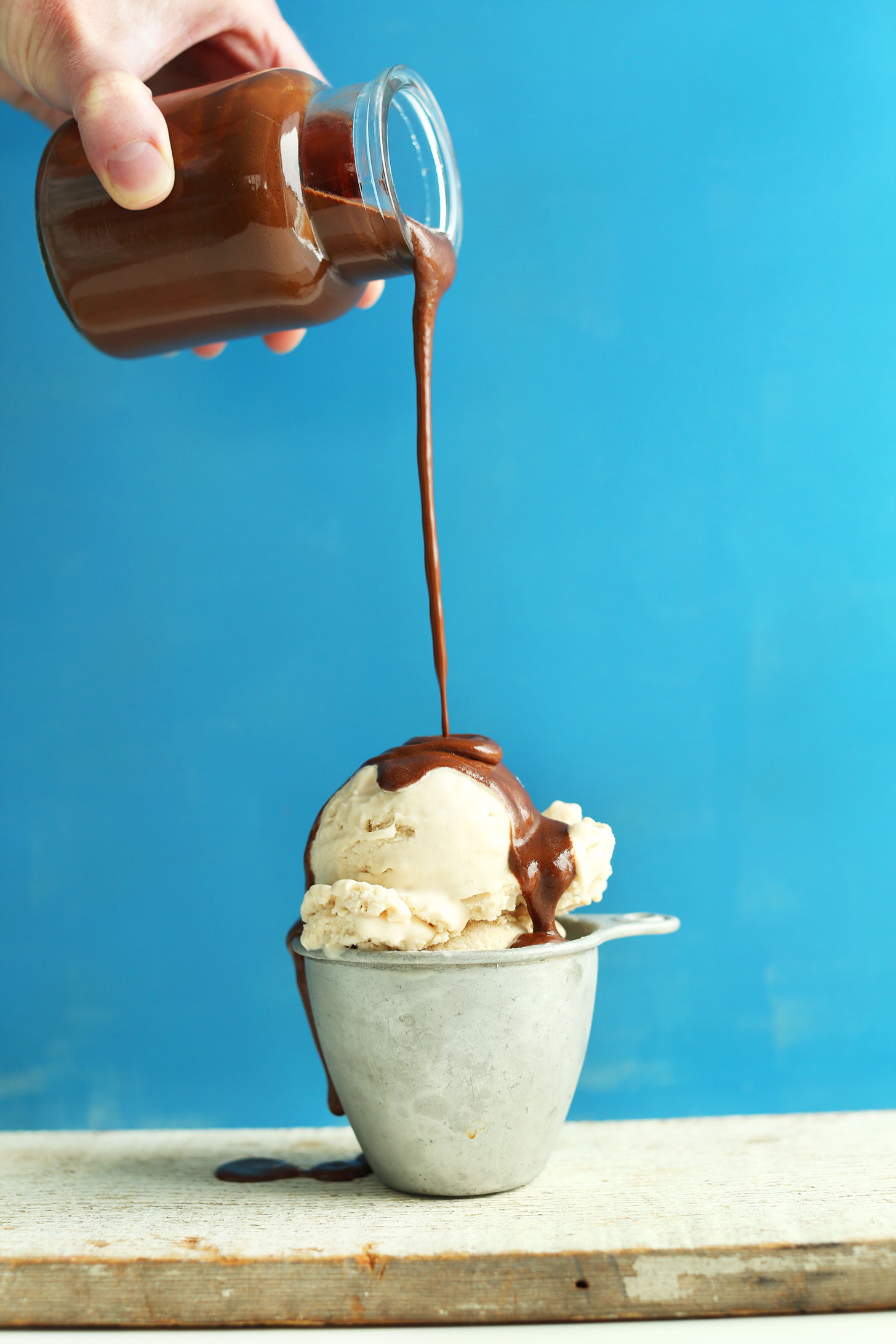 Pouring our homemade gluten-free naturally-sweetened chocolate sauce over a scoop of vegan ice cream