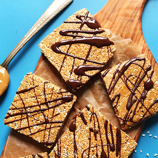 Parchment-lined cutting board with several squares of our Vegan Protein Bar recipe drizzled with melted chocolate