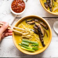 Using chopsticks to pick up a bite of delicious Coconut Curry Ramen