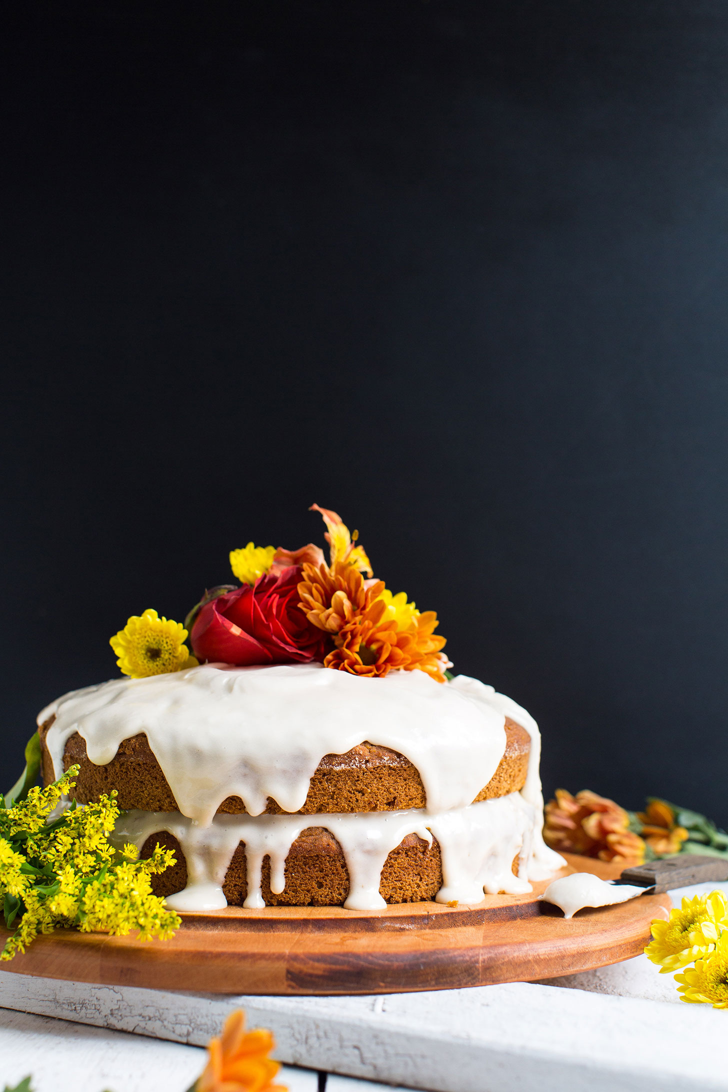 Two-layered gluten-free vegan Pumpkin Cake topped with frosting and flowers