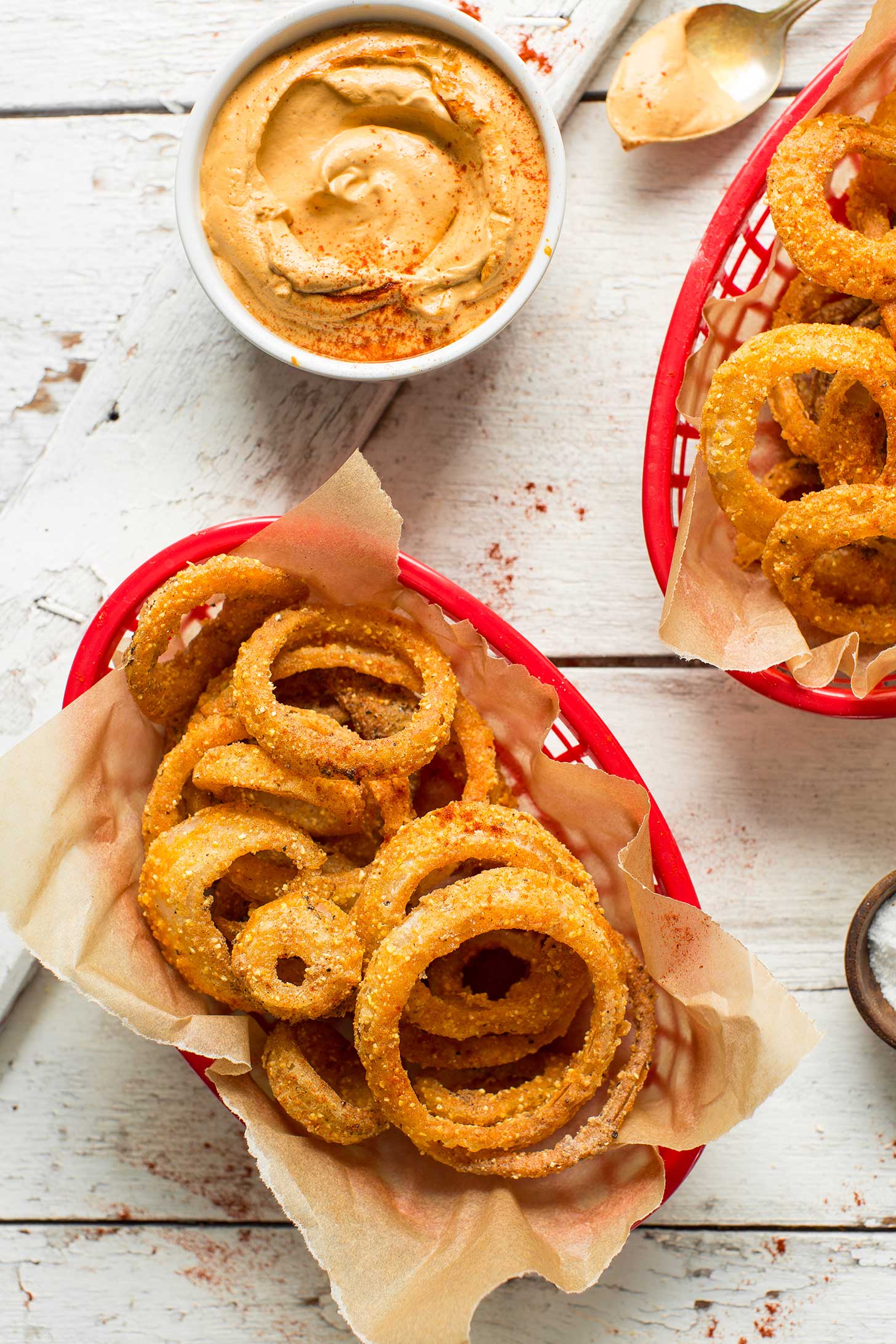 Two bowls of crispy gluten-free Onion Rings and a side of vegan Chipotle Aioli