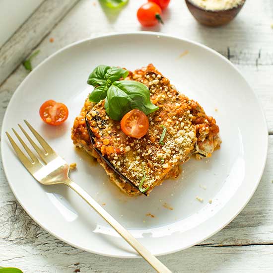 Plate with a slice of Lentil & Eggplant Lasagna topped with fresh basil