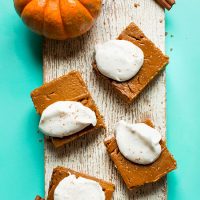 Distressed white wood board topped with Creamy Vegan Pumpkin Pie Bars