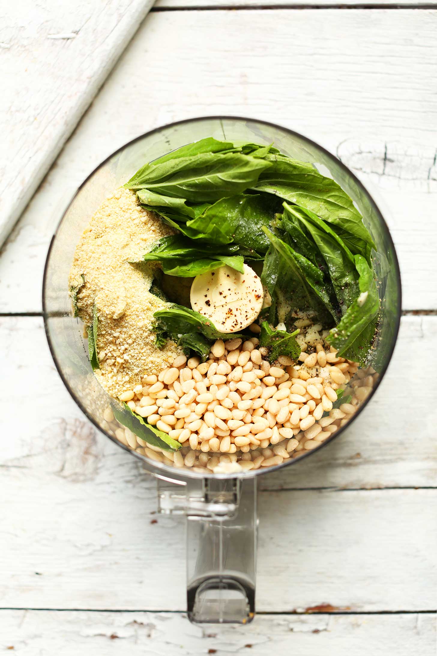 Food processor with ingredients for making basil pesto