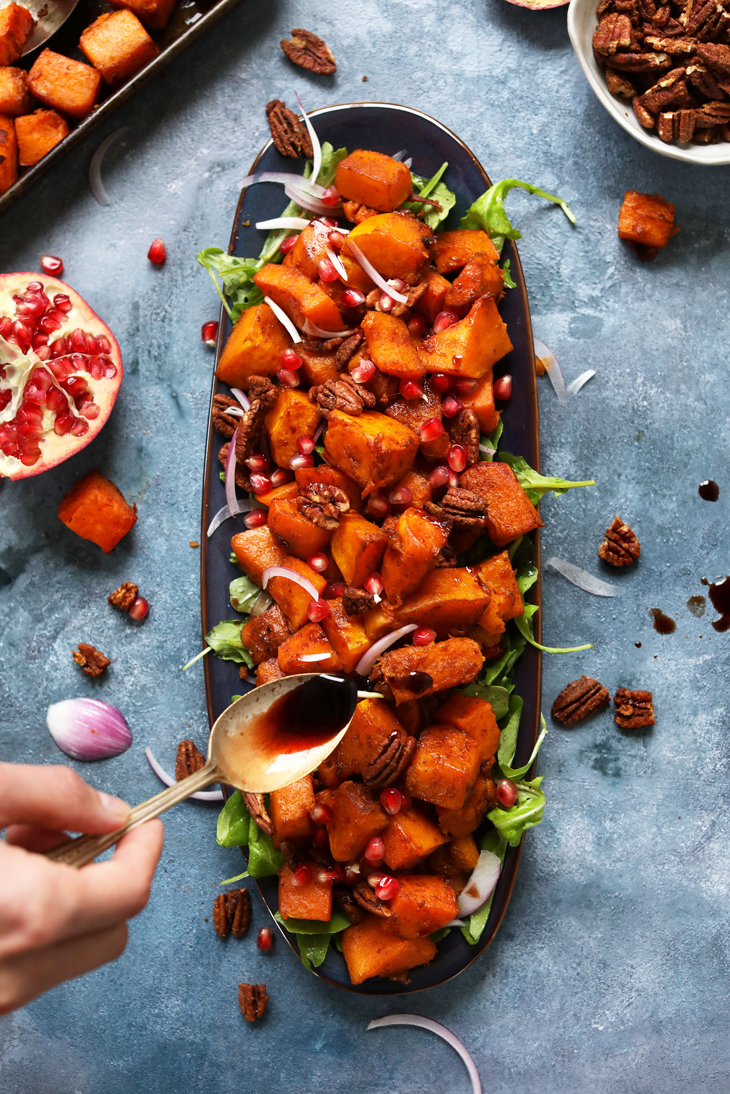 Drizzling pomegranate molasses over our Sweet Spicy Roasted Squash Salad with Cinnamon Sugar Pecans