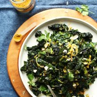 Big plate of Coconut Curried Greens beside a spoonful of curry powder
