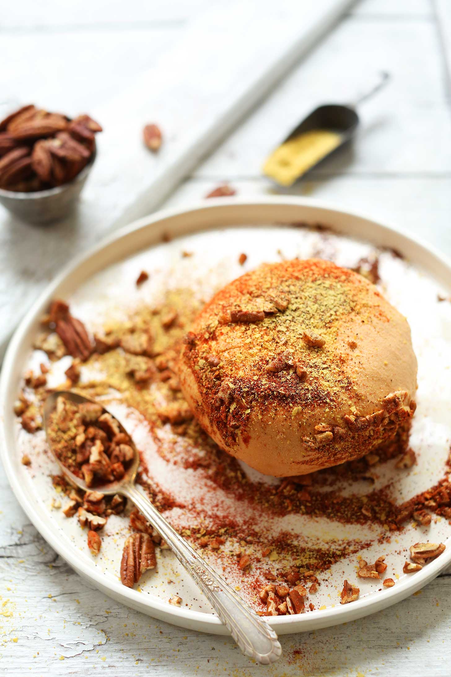 Plate with Spicy Vegan Cheese Ball topped with nuts and spices