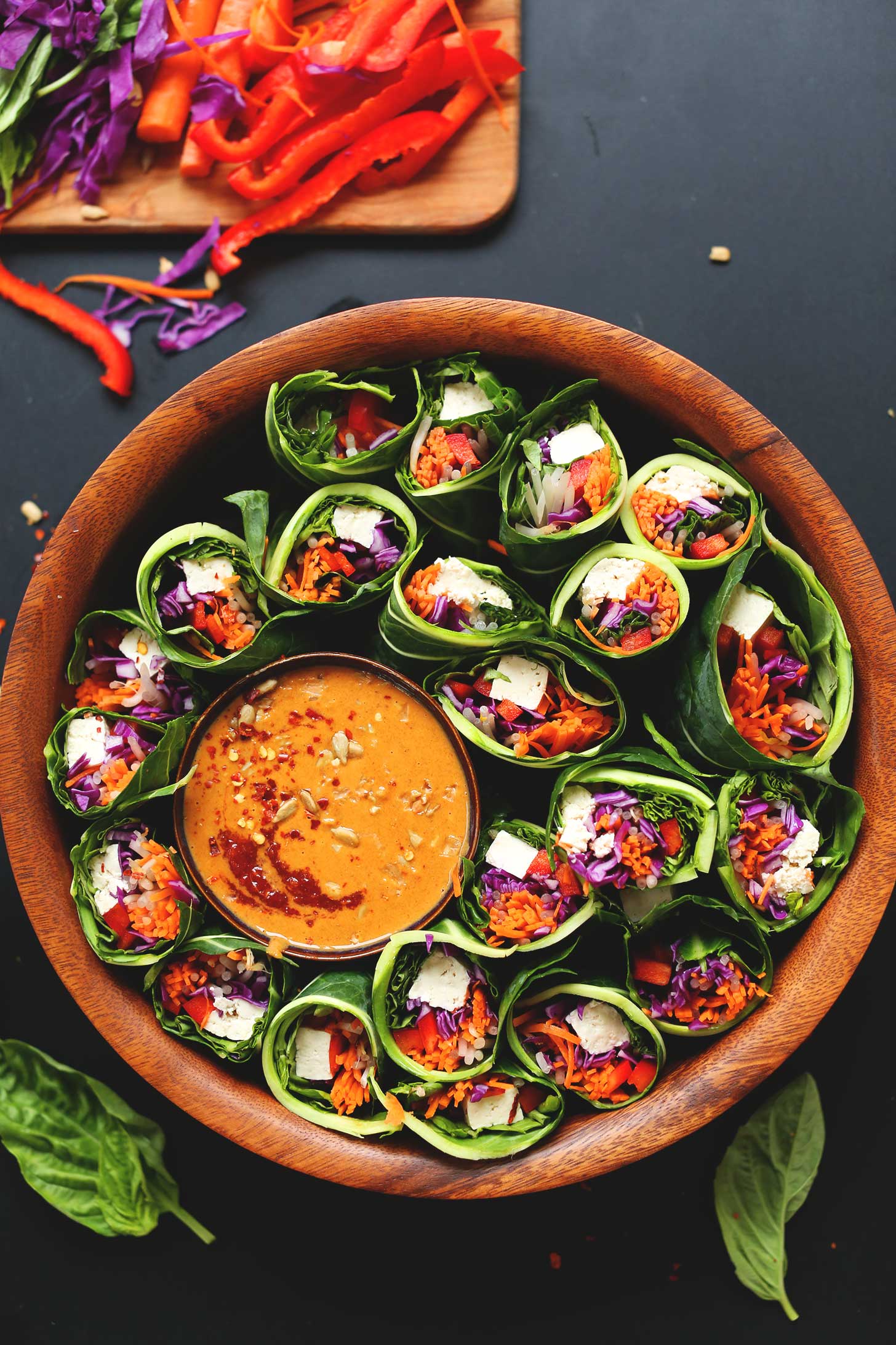 Big wood bowl filled with Collard Green, Veggie, + Tofu Spring Rolls and Sunbutter Dipping Sauce