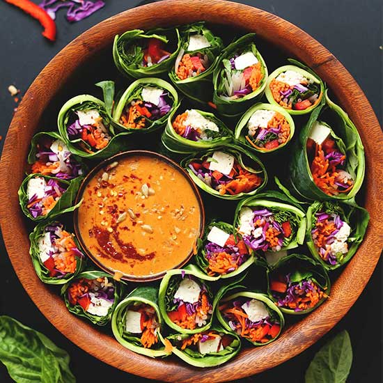 Collard Green Spring Rolls in a wood bowl with dipping sauce