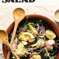 Serving spoons resting on a bowl of our 5-minute green salad with no-mix tahini dressing