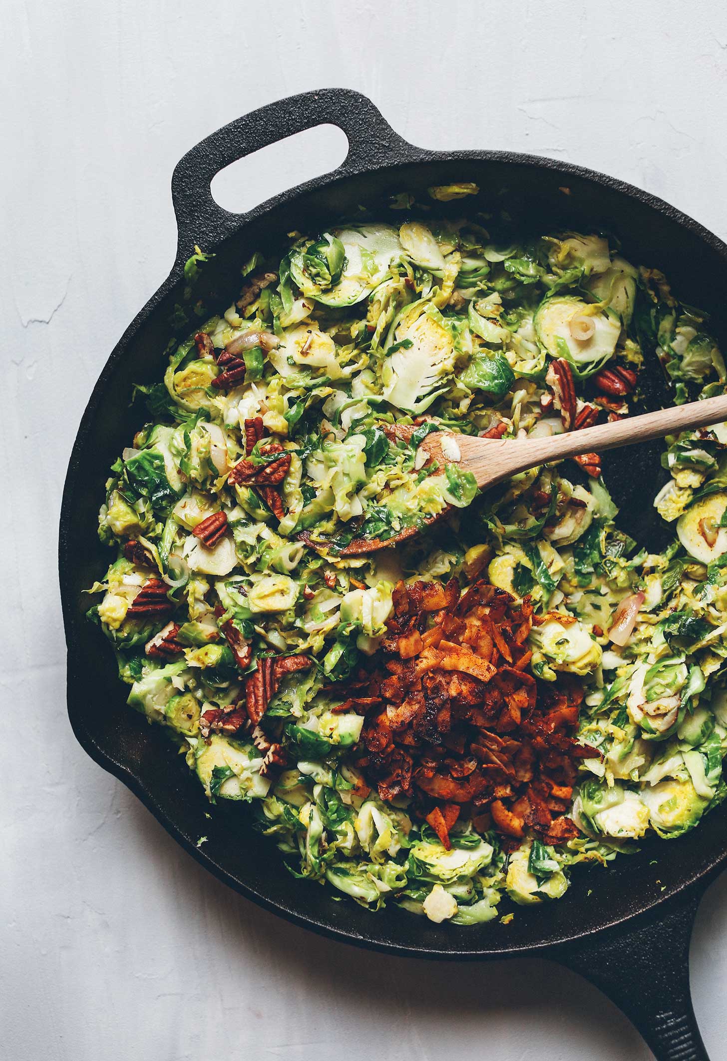 Adding vegan coconut bacon and pecans to our Warm Brussels Sprout Slaw recipe