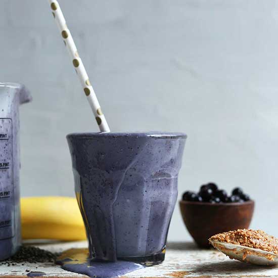 Overflowing glass of our Blueberry Almond Butter Smoothie recipe