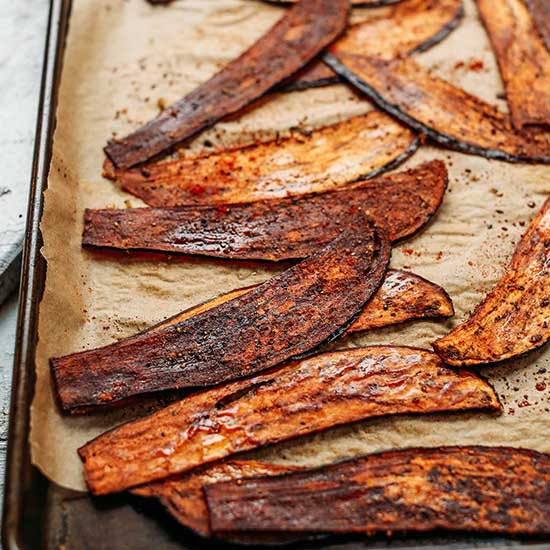 Slices of Crispy Eggplant "Bacon" on a parchment-lined baking sheet