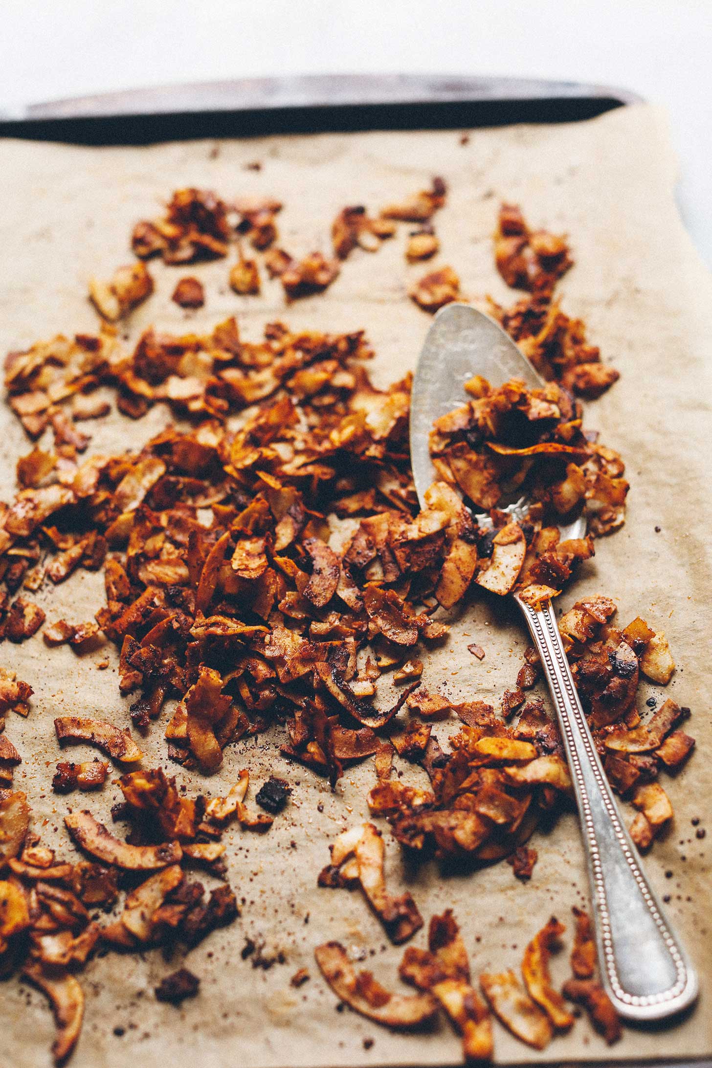 Baking sheet of homemade Vegan Coconut Bacon and a serving spoon